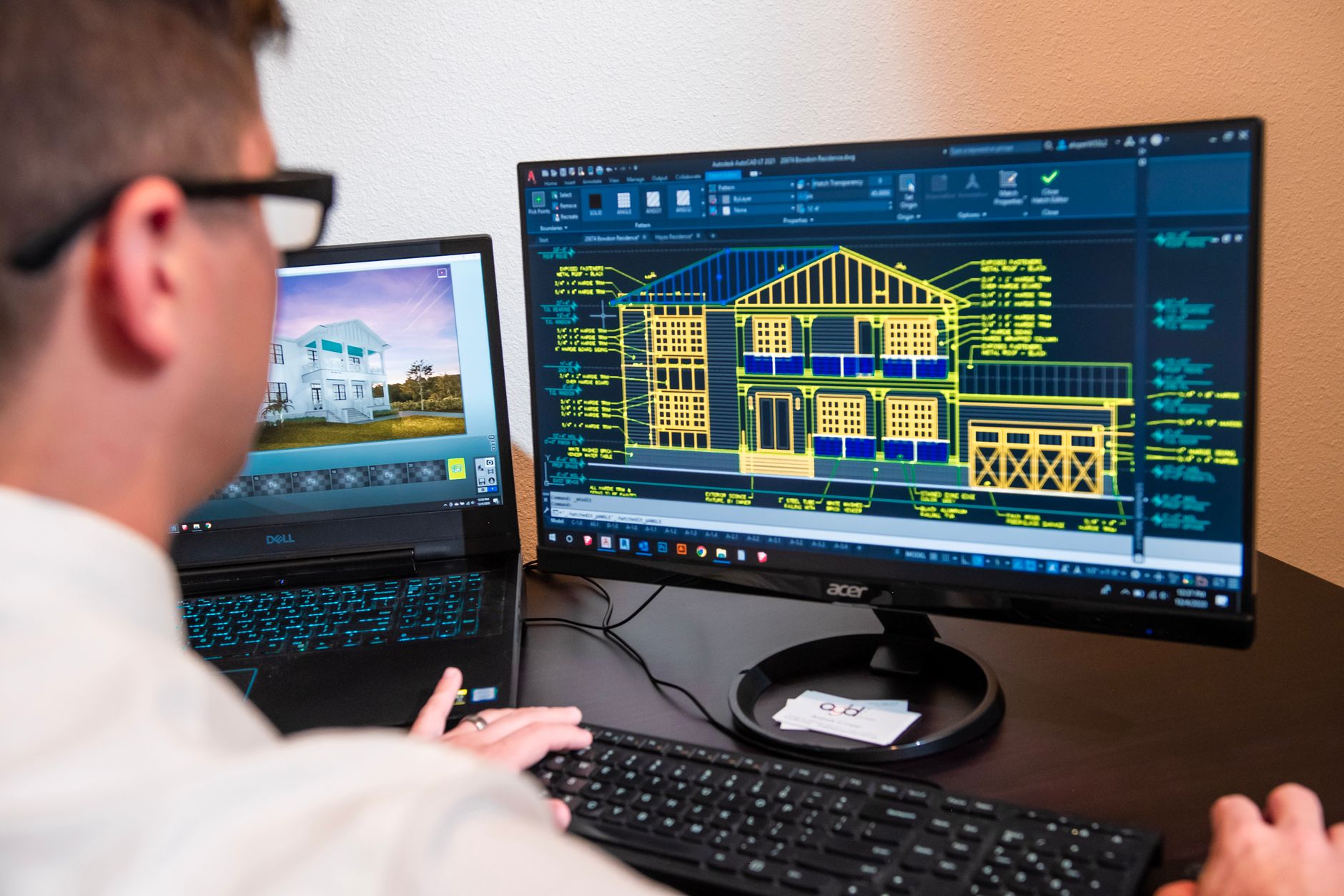 Un architecte compare des plans techniques dessinés avec un logiciel de CAO sur deux écrans
