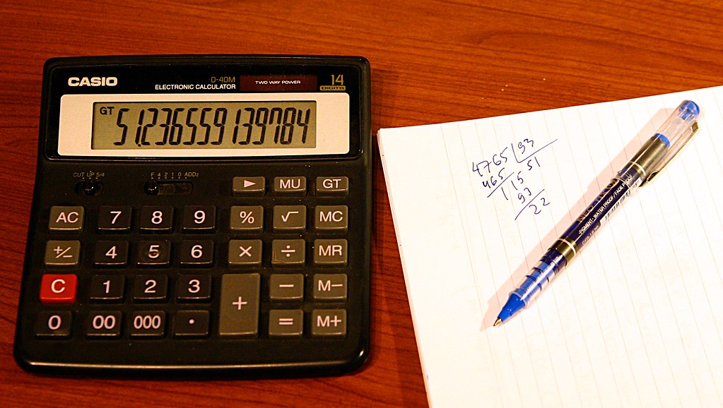 Calculatrice et notes de calcul manuscrites sur un bureau en bois