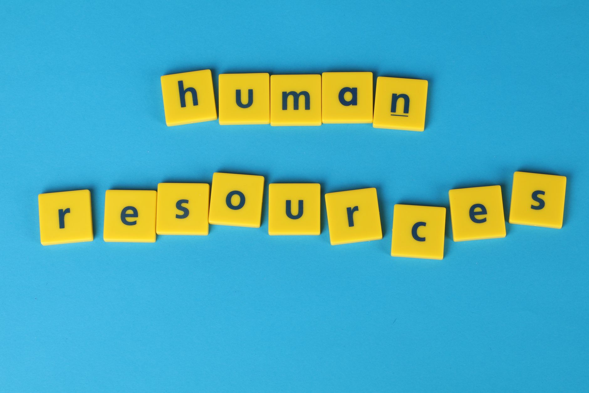 Lettres jaunes formant les mots human resources sur fond bleu, symbole des ressources humaines