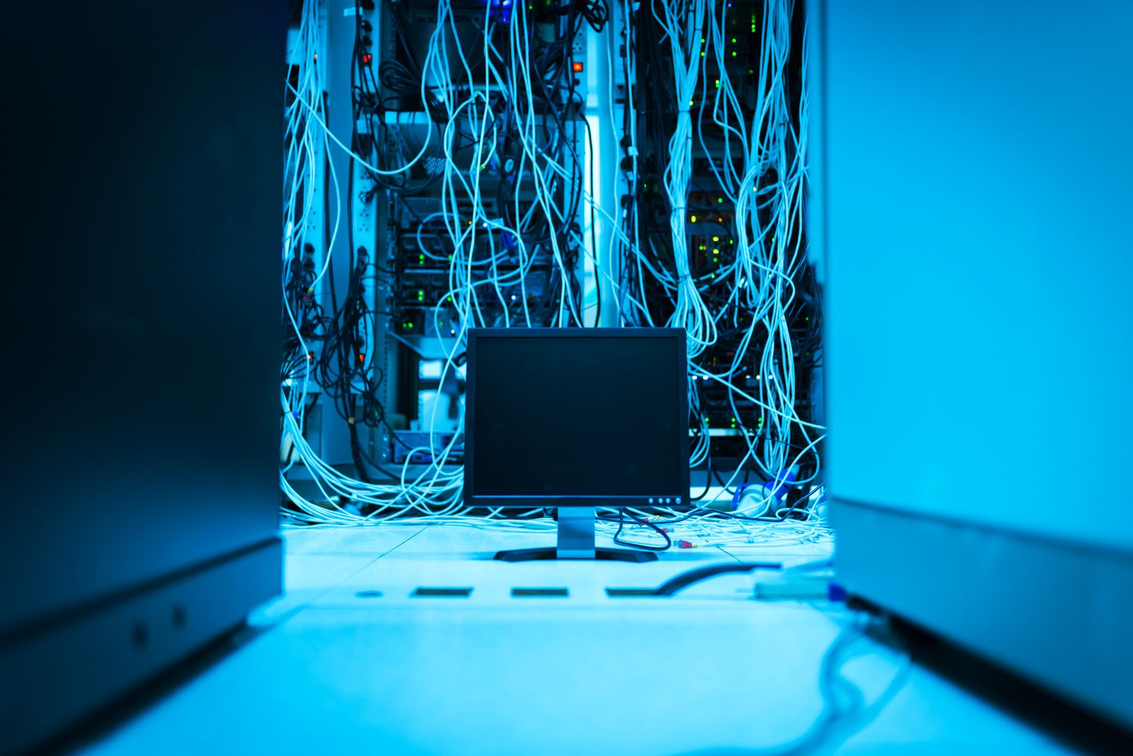 Screen connected to a server rack through a tangle of cables, symbolising system interconnection