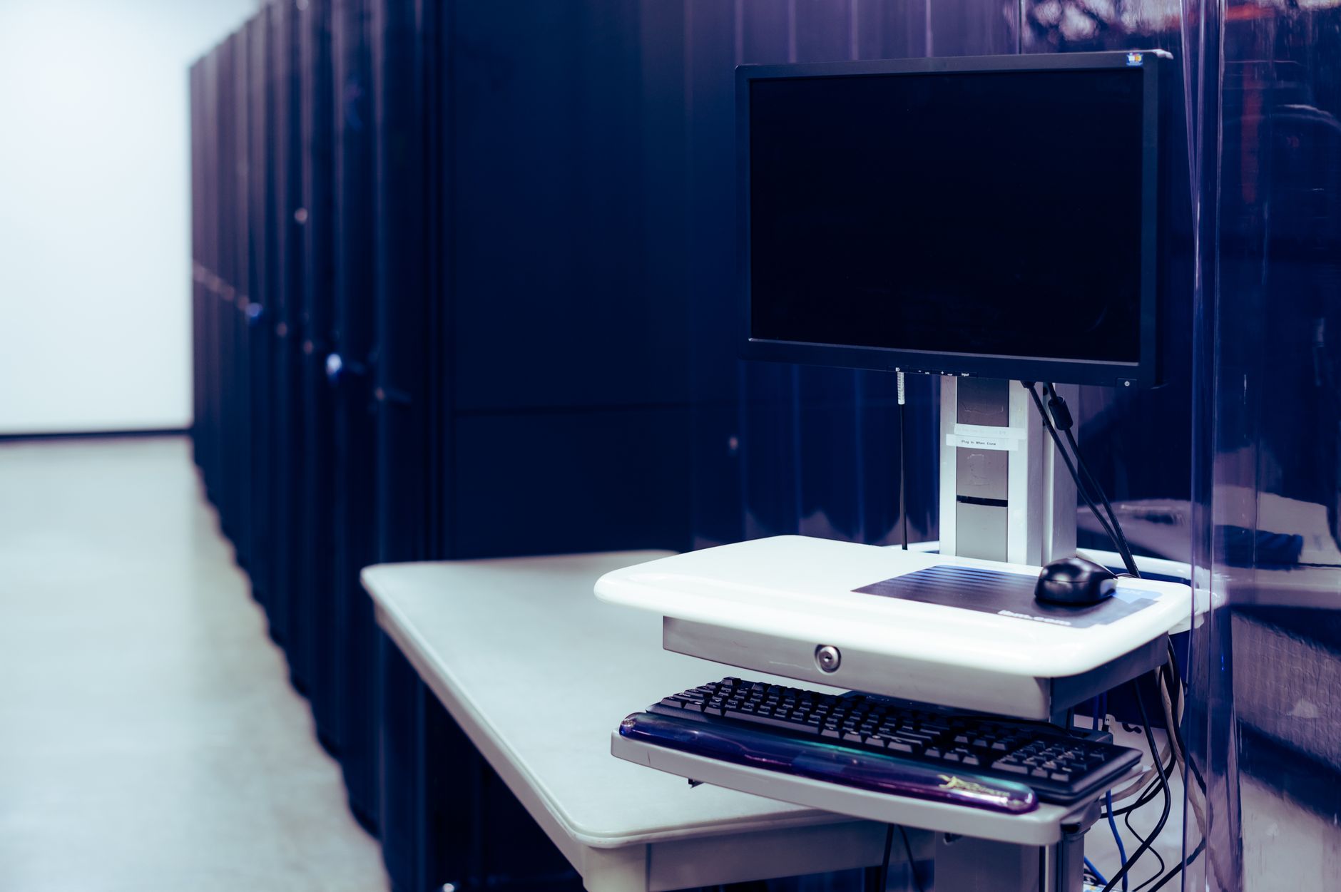 Poste de travail informatique face à une baie de serveurs dans un centre de données